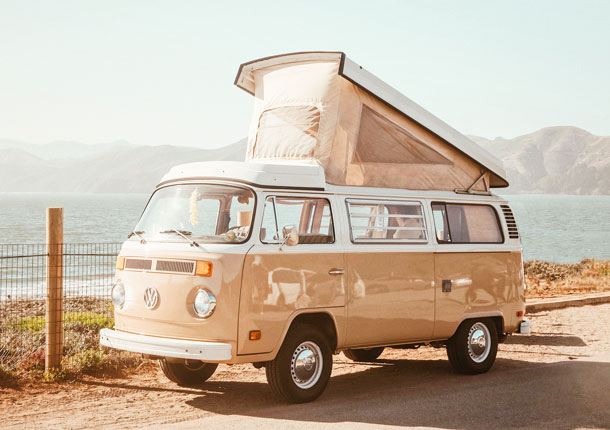 Sandfarbener VW Bus am Meer, Sinnbild für Freiheit